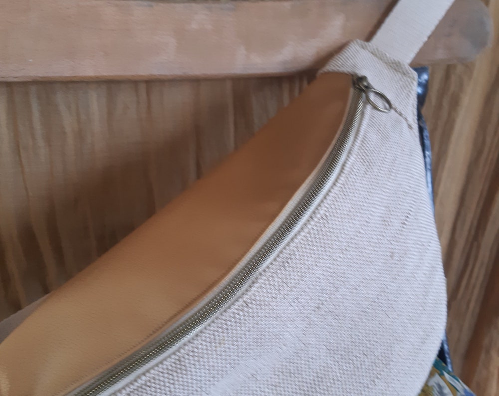 Bum bag, in natural beige coated linen fabric and gold imitation flap. Matching interior fabric (depending on stock) or plain beige.